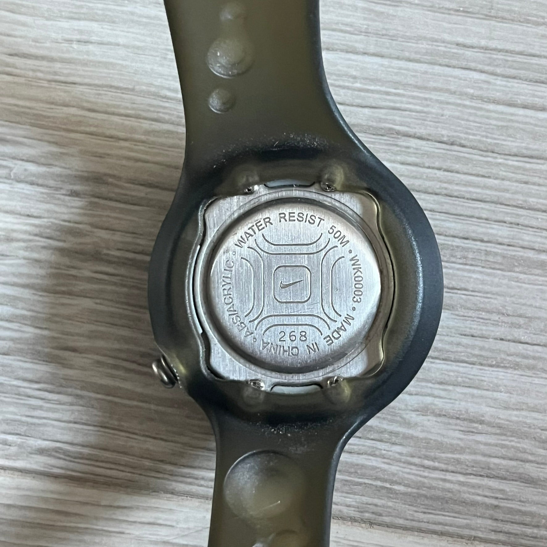 A minimalist timepiece from Nike, the Jelly Bean WK0003 stands out with its transparent dark strap filled with intentional bubble accents. The small analog face continues the theme with subtle grey bubble details, creating a sleek and unconventional design.