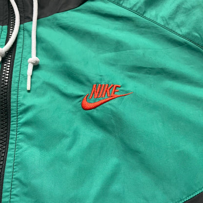 Nike Kenya Olympics Split Windbreaker from 2008, created by designer Jarrett Reynolds. Crafted in black and green. Small Maasai shield on one side of the chest with Nike red embroidery on the other. The upper half of the jacket is green, bottom and arms are fully black. This innovative jacket can be zipped apart on both sides and merged with other compatible models. Hidden inside, a small Kenya flags accent completes the concept.