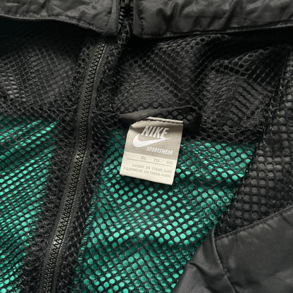 Nike Kenya Olympics Split Windbreaker from 2008, created by designer Jarrett Reynolds. Crafted in black and green. Small Maasai shield on one side of the chest with Nike red embroidery on the other. The upper half of the jacket is green, bottom and arms are fully black. This innovative jacket can be zipped apart on both sides and merged with other compatible models. Hidden inside, a small Kenya flags accent completes the concept.