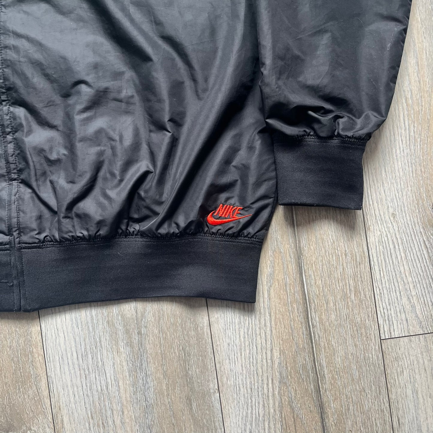Nike Kenya Olympics Split Windbreaker from 2008, created by designer Jarrett Reynolds. Crafted in black and green. Small Maasai shield on one side of the chest with Nike red embroidery on the other. The upper half of the jacket is green, bottom and arms are fully black. This innovative jacket can be zipped apart on both sides and merged with other compatible models. Hidden inside, a small Kenya flags accent completes the concept.