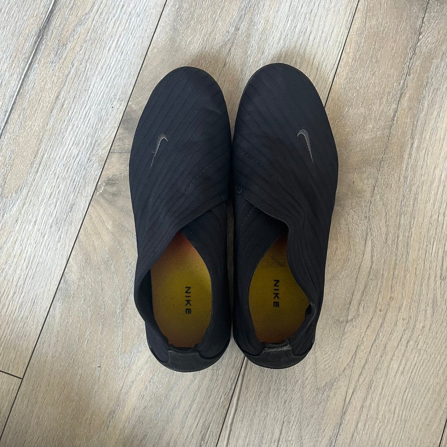 Nike Kyoto 2002 Slip-On Black Shoe is a slip-on model released in 2002, featuring a woven stretch upper with an embroidered Swoosh and stitched medial detailing. The design includes a nubuck panel with embossed Nike script and a patterned upper inspired by Zen garden textures, paired with a contrasting orange outsole. This model was part of Nike’s early performance-focused footwear line connected to yoga-inspired design.