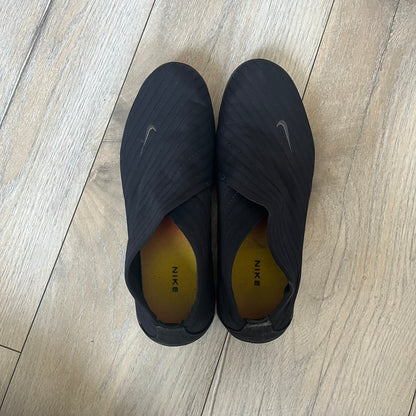 Nike Kyoto 2002 Slip-On Black Shoe is a slip-on model released in 2002, featuring a woven stretch upper with an embroidered Swoosh and stitched medial detailing. The design includes a nubuck panel with embossed Nike script and a patterned upper inspired by Zen garden textures, paired with a contrasting orange outsole. This model was part of Nike’s early performance-focused footwear line connected to yoga-inspired design.