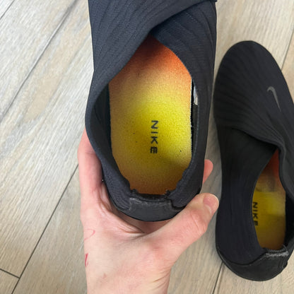 Nike Kyoto 2002 Slip-On Black Shoe is a slip-on model released in 2002, featuring a woven stretch upper with an embroidered Swoosh and stitched medial detailing. The design includes a nubuck panel with embossed Nike script and a patterned upper inspired by Zen garden textures, paired with a contrasting orange outsole. This model was part of Nike’s early performance-focused footwear line connected to yoga-inspired design.