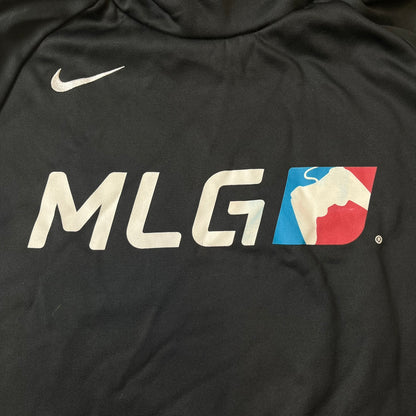 Nike MLG (Major League Gaming) Black Hoodie is a performance hoodie made from 100% polyester with Nike Dri-FIT technology. It features a kangaroo pocket, a Nike Swoosh on the upper right chest, and a large Major League Gaming (MLG) logo across the center with the iconic red and blue gamepad graphic. The hood has a raised front design that extends to cover the mouth.