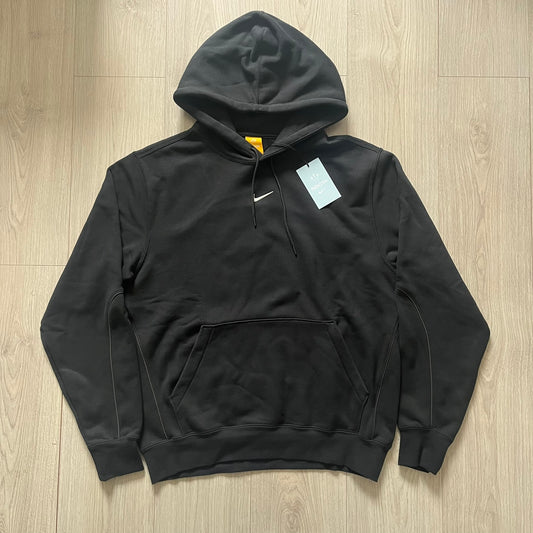 Nike x Nocta Fleece CS Hoodie in Black combines Drake’s refined streetwear vision with Nike’s premium craftsmanship. Made from an ultra-soft fleece blend, it features reflective piping, a silicone Swoosh logo and discreet NOCTA branding. With an adjustable hood, kangaroo pocket, and hidden zip pocket, this piece balances luxury comfort and technical precision.
