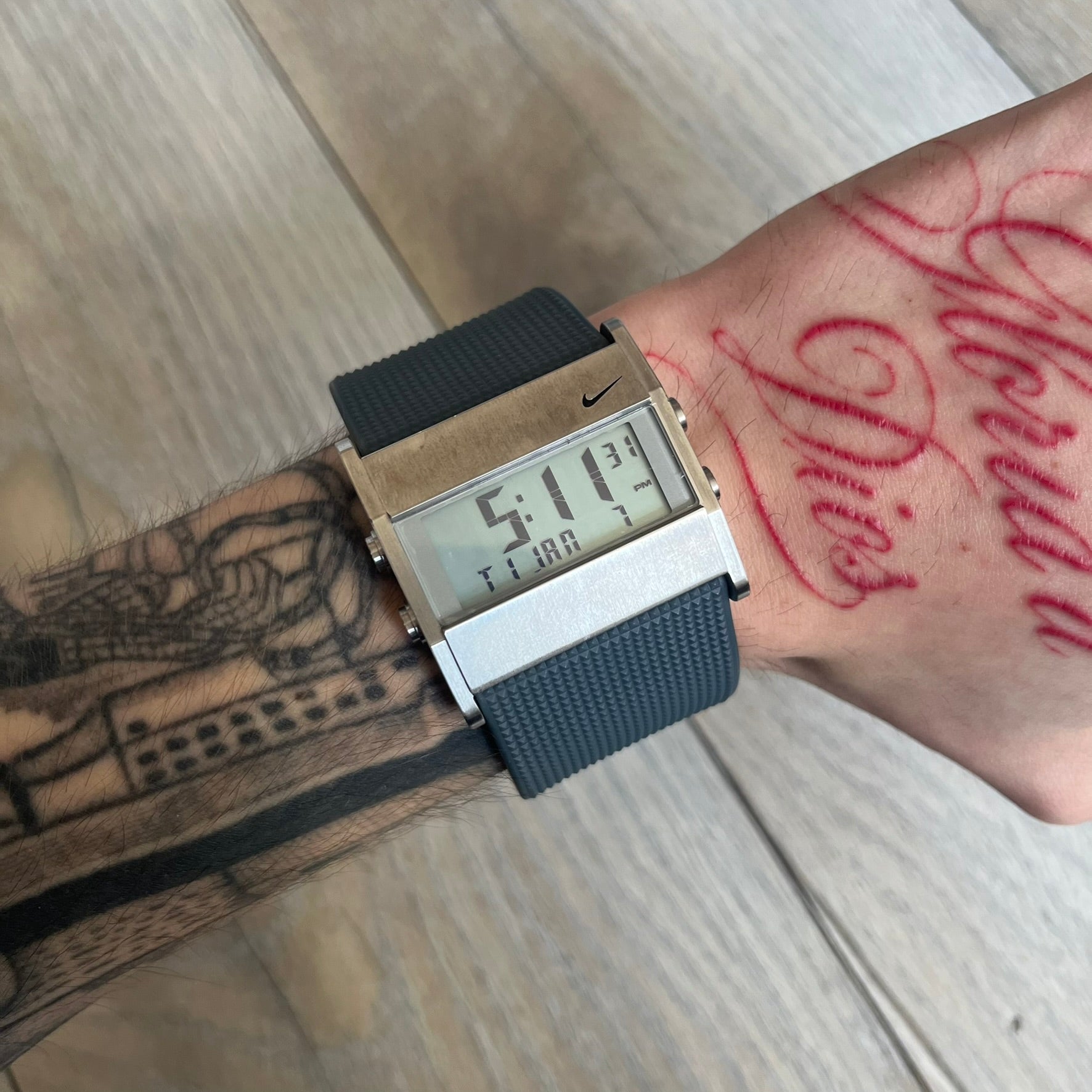 Nike Oregon Series Gray Digital Watch is a digital wristwatch featuring a rectangular display with a stainless steel frame and a dark grey rubber strap with stainless steel clasp. The watch includes four side buttons, backlight function, and displays black digital numerals, with a small Nike logo on the metal bezel. It is water resistant up to 100 meters, powered by fresh batteries, and comes with original tag and box.