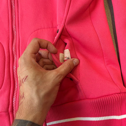 Nike Pink Women's Bomber-style Zip-up features a pink, heavyweight cotton construction with a tall black collar. It has a full front zipper with a circular zipper pull and two front Velcro pockets, one with a small Nike tag. The garment has a jacket-style construction.

