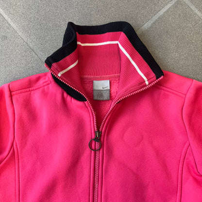 Nike Pink Women's Bomber-style Zip-up features a pink, heavyweight cotton construction with a tall black collar. It has a full front zipper with a circular zipper pull and two front Velcro pockets, one with a small Nike tag. The garment has a jacket-style construction.
