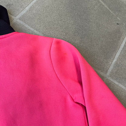 Nike Pink Women's Bomber-style Zip-up features a pink, heavyweight cotton construction with a tall black collar. It has a full front zipper with a circular zipper pull and two front Velcro pockets, one with a small Nike tag. The garment has a jacket-style construction.
