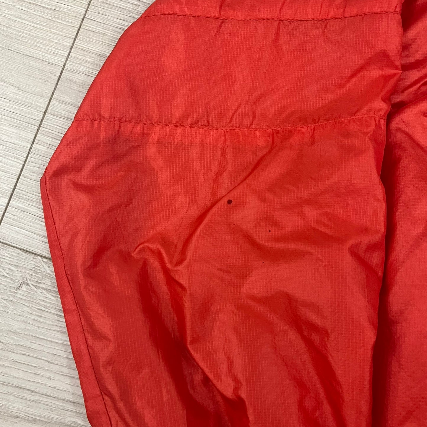 Nike Red/Blue/White Split Windbreaker featuring a modular design with front and back zippers that allow attachment to compatible jackets. The layout includes dominant red panels across the sleeves and upper front, contrasted with blue accents, a white hood, and a blue-white-black camo hood lining. Finished with a gold embroidered Nike logo on the chest.