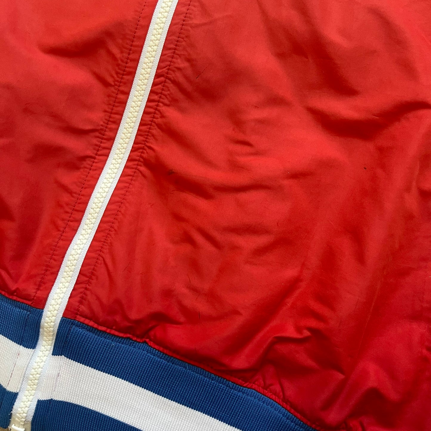 Nike Russia Olympics Split Windbreaker from 2008, created by designer Jarrett Reynolds. Crafted in a red, blue and white color wave. White Nike embroidery swoosh on the left side of the chest. The upper half of the jacket is blue with white hood, and the bottom is red with white accents. This innovative jacket can be zipped apart on both sides and merged with other compatible models. Hidden inside, a small Russia flags accent completes the concept.