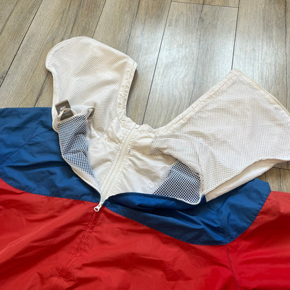 Nike Russia Olympics Split Windbreaker from 2008, created by designer Jarrett Reynolds. Crafted in a red, blue and white color wave. White Nike embroidery swoosh on the left side of the chest. The upper half of the jacket is blue with white hood, and the bottom is red with white accents. This innovative jacket can be zipped apart on both sides and merged with other compatible models. Hidden inside, a small Russia flags accent completes the concept.