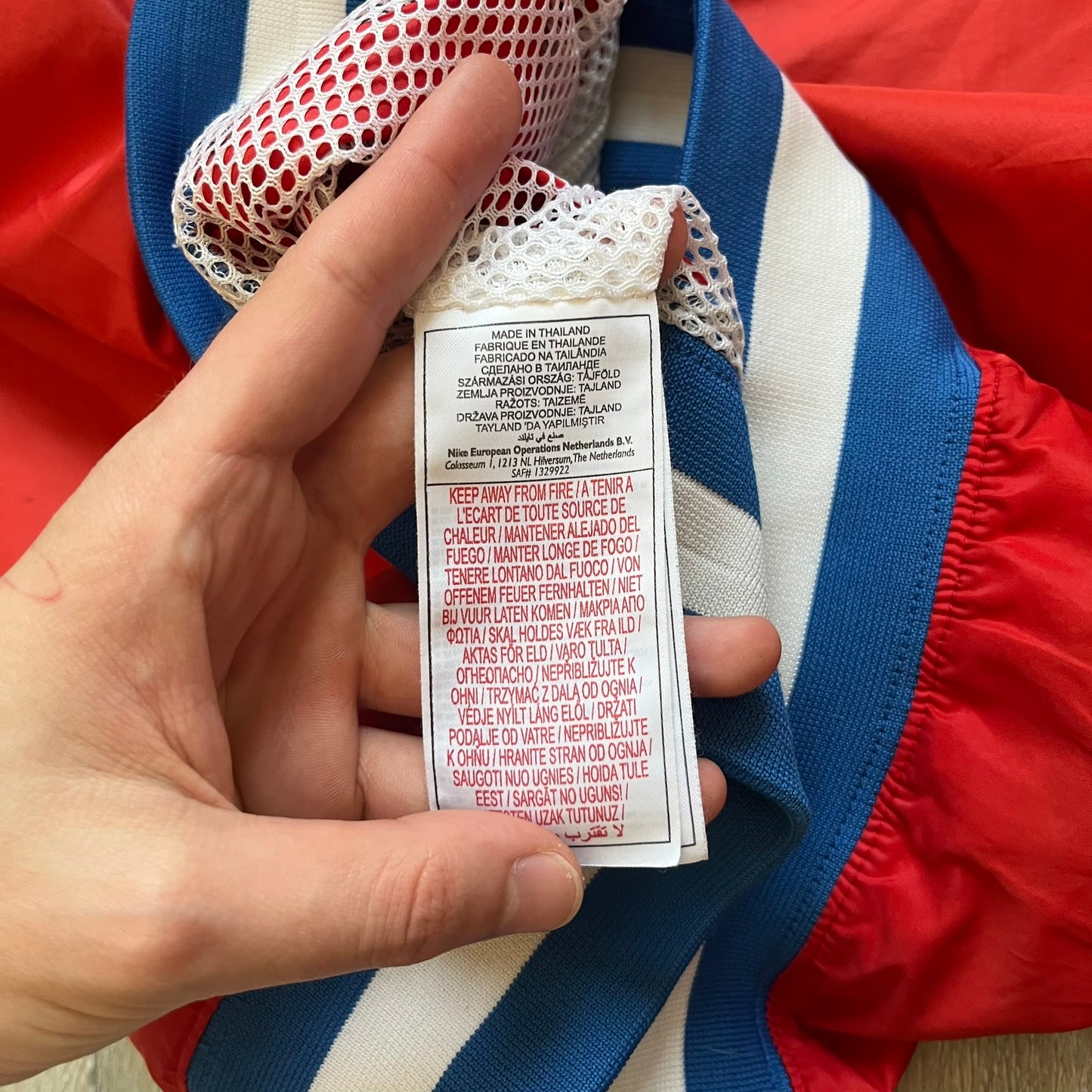 Nike Russia Olympics Split Windbreaker from 2008, created by designer Jarrett Reynolds. Crafted in a red, blue and white color wave. White Nike embroidery swoosh on the left side of the chest. The upper half of the jacket is blue with white hood, and the bottom is red with white accents. This innovative jacket can be zipped apart on both sides and merged with other compatible models. Hidden inside, a small Russia flags accent completes the concept.