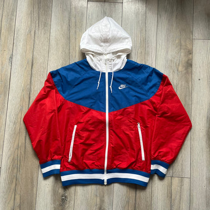 Nike Russia Olympics Split Windbreaker from 2008, created by designer Jarrett Reynolds. Crafted in a red, blue and white color wave. White Nike embroidery swoosh on the left side of the chest. The upper half of the jacket is blue with white hood, and the bottom is red with white accents. This innovative jacket can be zipped apart on both sides and merged with other compatible models. Hidden inside, a small Russia flags accent completes the concept.