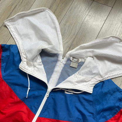 Nike Russia Olympics Split Windbreaker from 2008, created by designer Jarrett Reynolds. Crafted in a red, blue and white color wave. White Nike embroidery swoosh on the left side of the chest. The upper half of the jacket is blue with white hood, and the bottom is red with white accents. This innovative jacket can be zipped apart on both sides and merged with other compatible models. Hidden inside, a small Russia flags accent completes the concept.