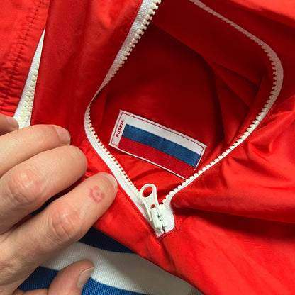 Nike Russia Olympics Split Windbreaker from 2008, created by designer Jarrett Reynolds. Crafted in a red, blue and white color wave. White Nike embroidery swoosh on the left side of the chest. The upper half of the jacket is blue with white hood, and the bottom is red with white accents. This innovative jacket can be zipped apart on both sides and merged with other compatible models. Hidden inside, a small Russia flags accent completes the concept.