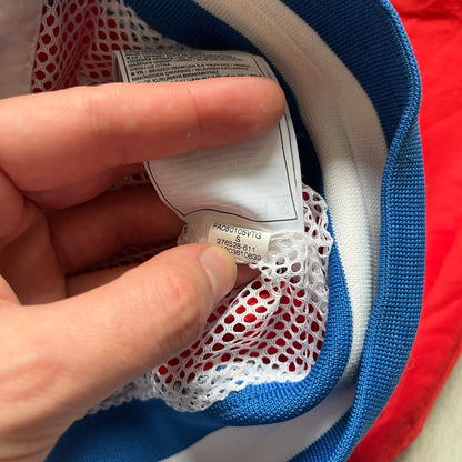 Nike Russia Olympics Split Windbreaker from 2008, created by designer Jarrett Reynolds. Crafted in a red, blue and white color wave. White Nike embroidery swoosh on the left side of the chest. The upper half of the jacket is blue with white hood, and the bottom is red with white accents. This innovative jacket can be zipped apart on both sides and merged with other compatible models. Hidden inside, a small Russia flags accent completes the concept.