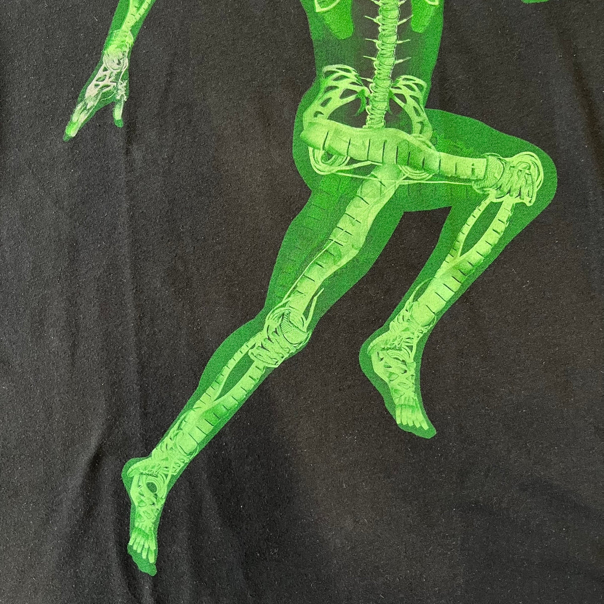 Nike SS11 "X-Ray Skeleton Free Faster" Tee is a black T-shirt from the Nike Free 2011 Spring/Summer season, designed by art director Kelvin Govey and designer Wonman Kim. The design features a large glow-in-the-dark green X-ray skeletal figure constructed entirely from parts of the Nike Free Run+2 shoe, with white Dri-FIT text at the bottom right and a green Nike Swoosh on the left sleeve.&nbsp;