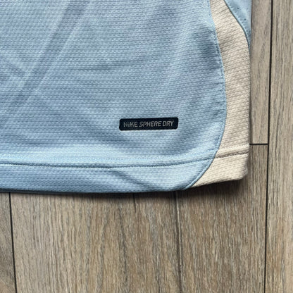 Nike Sphere Dry 90’s Baby Blue Tee is a baby blue T-shirt featuring gray and white stripe detailing. The front includes a dark gray Nike logo alongside a “90” graphic, with an additional Nike logo on the sleeve. The back displays a large light blue “90” print