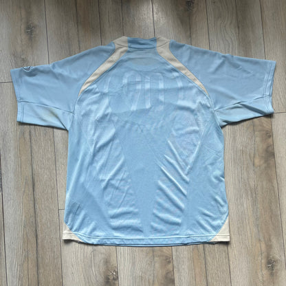 Nike Sphere Dry 90’s Baby Blue Tee is a baby blue T-shirt featuring gray and white stripe detailing. The front includes a dark gray Nike logo alongside a “90” graphic, with an additional Nike logo on the sleeve. The back displays a large light blue “90” print
