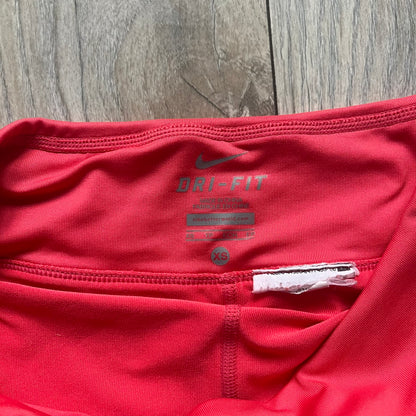 Nike Tie Break Knit 2012 Coral Tennis Skirt is a women’s tennis skort in coral featuring an integrated inner shorts layer. The skirt has a flared, creased design at the sides and a white Nike Swoosh at the lower hem. Designed for sporty performance, it combines lightweight knit construction with Nike’s 2012 Tie Break tennis line styling.