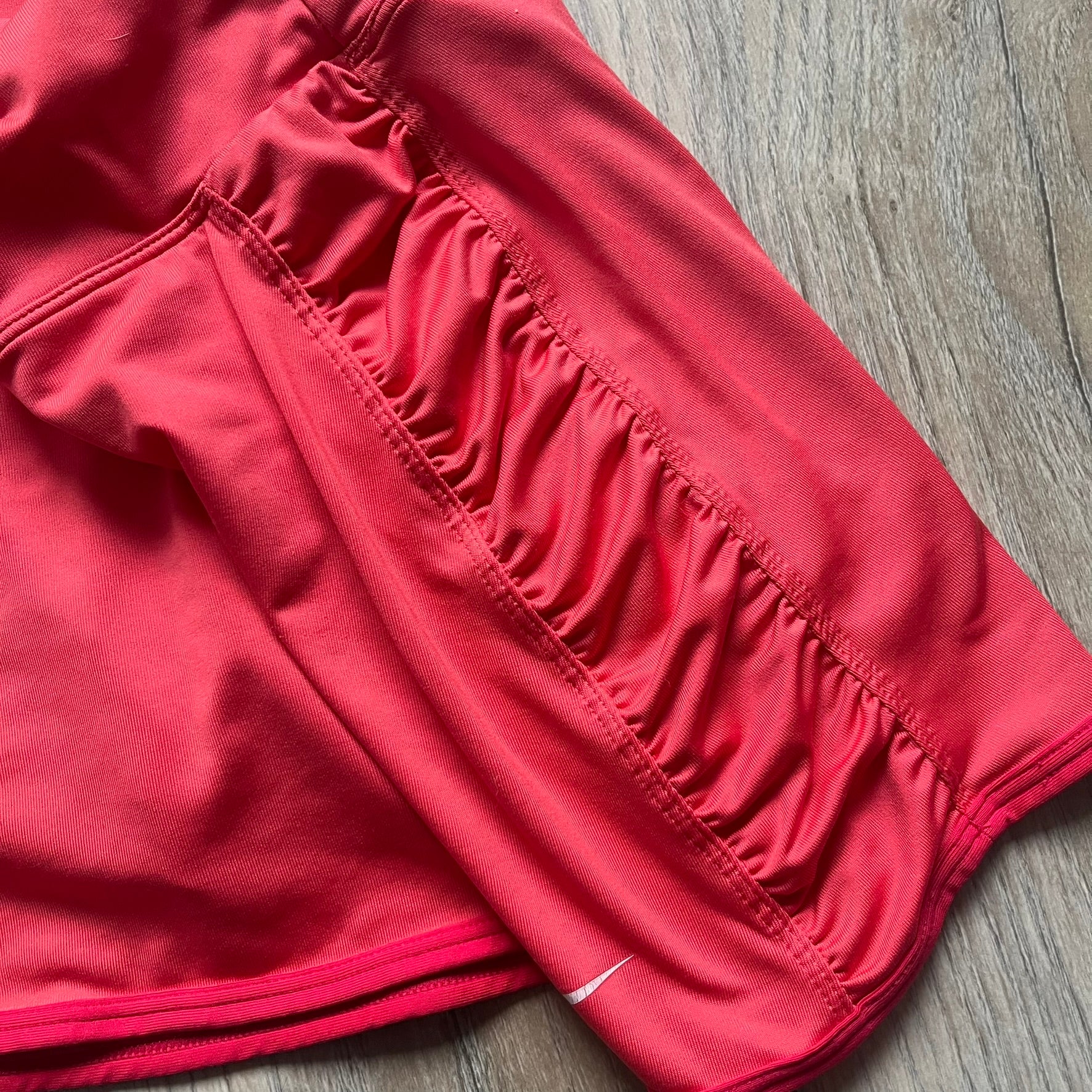 Nike Tie Break Knit 2012 Coral Tennis Skirt is a women’s tennis skort in coral featuring an integrated inner shorts layer. The skirt has a flared, creased design at the sides and a white Nike Swoosh at the lower hem. Designed for sporty performance, it combines lightweight knit construction with Nike’s 2012 Tie Break tennis line styling.