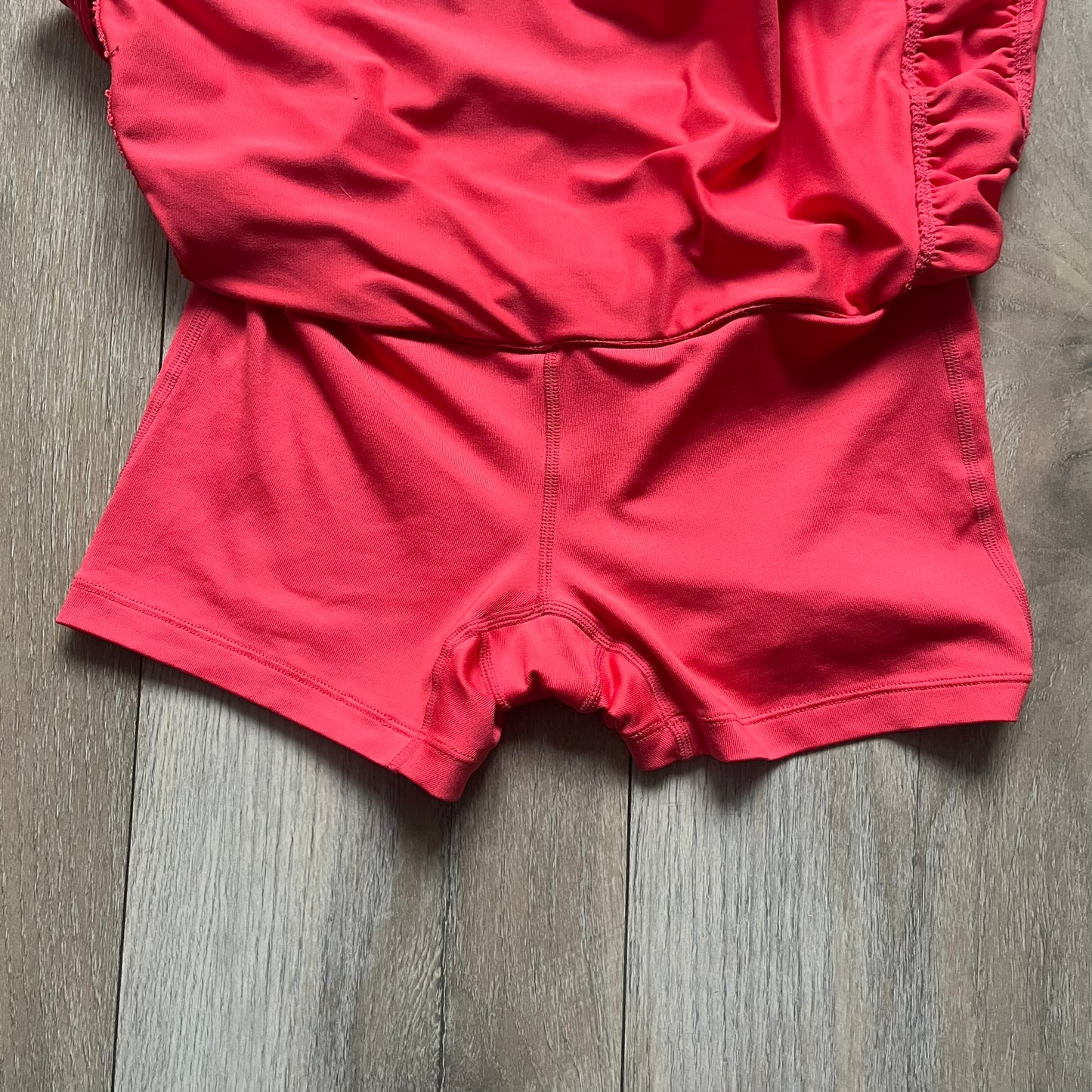 Nike Tie Break Knit 2012 Coral Tennis Skirt is a women’s tennis skort in coral featuring an integrated inner shorts layer. The skirt has a flared, creased design at the sides and a white Nike Swoosh at the lower hem. Designed for sporty performance, it combines lightweight knit construction with Nike’s 2012 Tie Break tennis line styling.