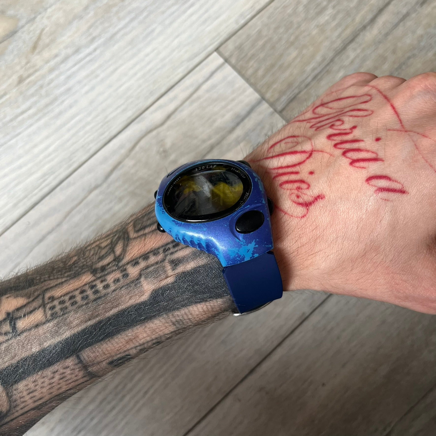 Nike Triax 120 WG40-0010 Digital Watch features a blue case with a black Nike Swoosh above the display and a black control button below it. The watch has a black digital screen with light-colored numerals and is fitted with navy-blue replacement straps that are not original Nike straps. Constructed from stainless steel and plastic materials, it offers 100-meter water resistance, 120-lap memory, and multiple timing and training modes.
