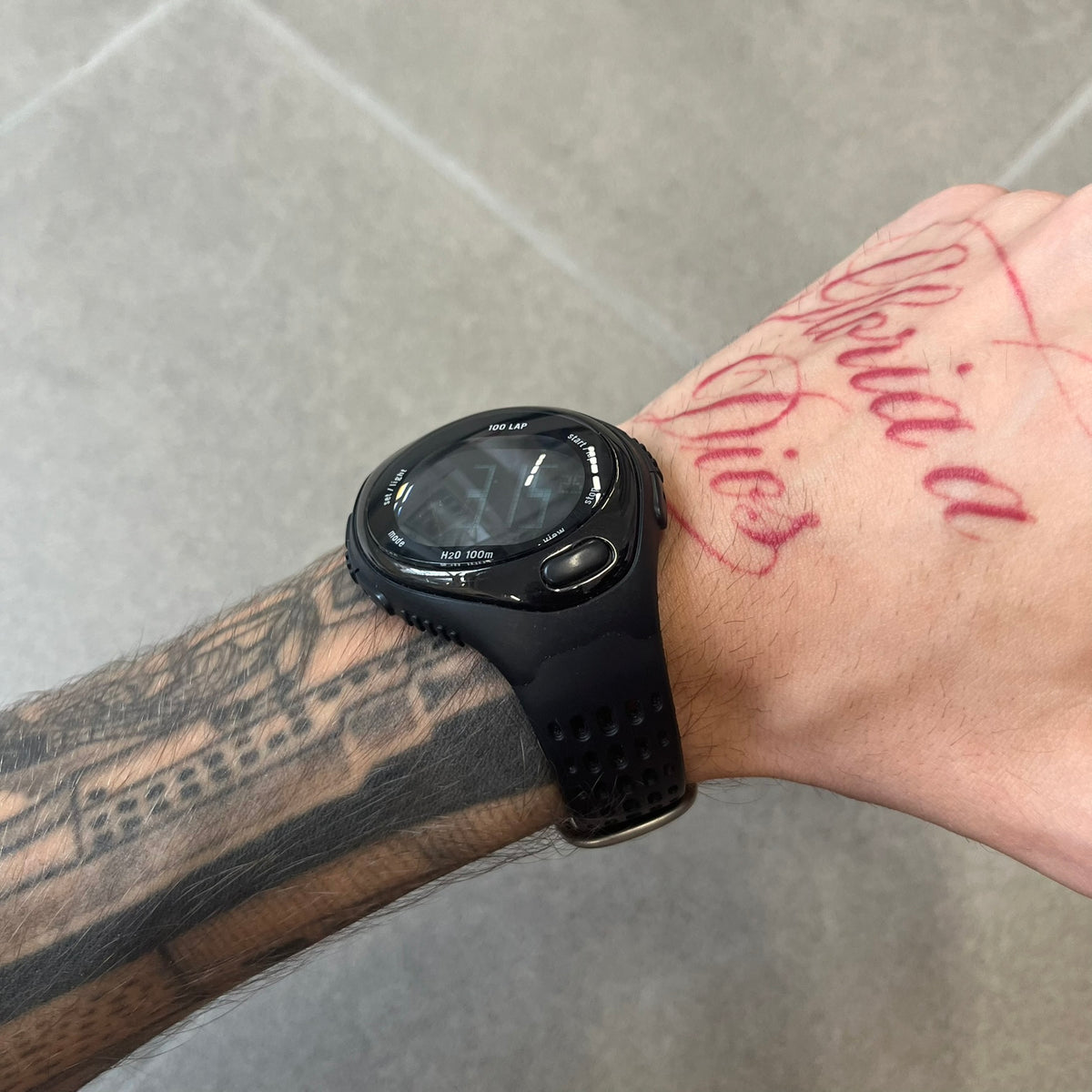 Nike Triax 2000's Bowerman Black Speed 100 Digital Watch features an all-black construction with rubber straps and a black digital display with light numerals. The case has a small Nike Swoosh at the top, while the watch includes 100-lap memory, multiple modes, and 100m water resistance.