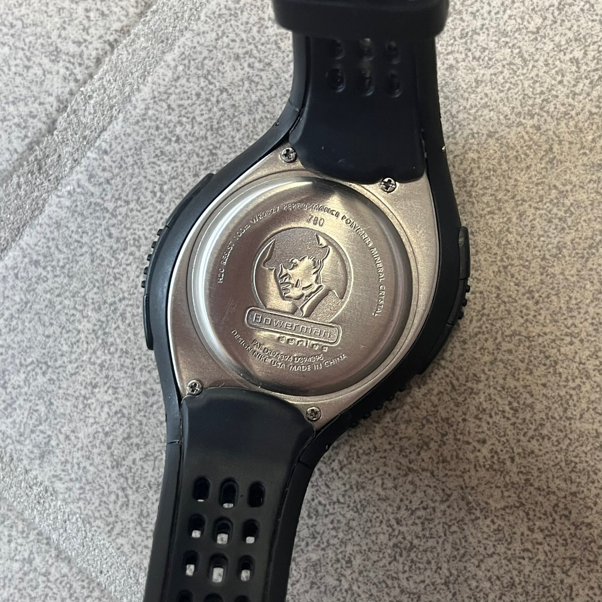 Nike Triax 2000's Bowerman Black Speed 100 Digital Watch features an all-black construction with rubber straps and a black digital display with light numerals. The case has a small Nike Swoosh at the top, while the watch includes 100-lap memory, multiple modes, and 100m water resistance.