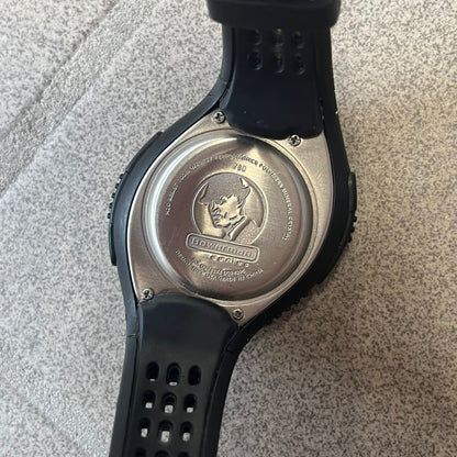 Nike Triax 2000's Bowerman Black Speed 100 Digital Watch features an all-black construction with rubber straps and a black digital display with light numerals. The case has a small Nike Swoosh at the top, while the watch includes 100-lap memory, multiple modes, and 100m water resistance.