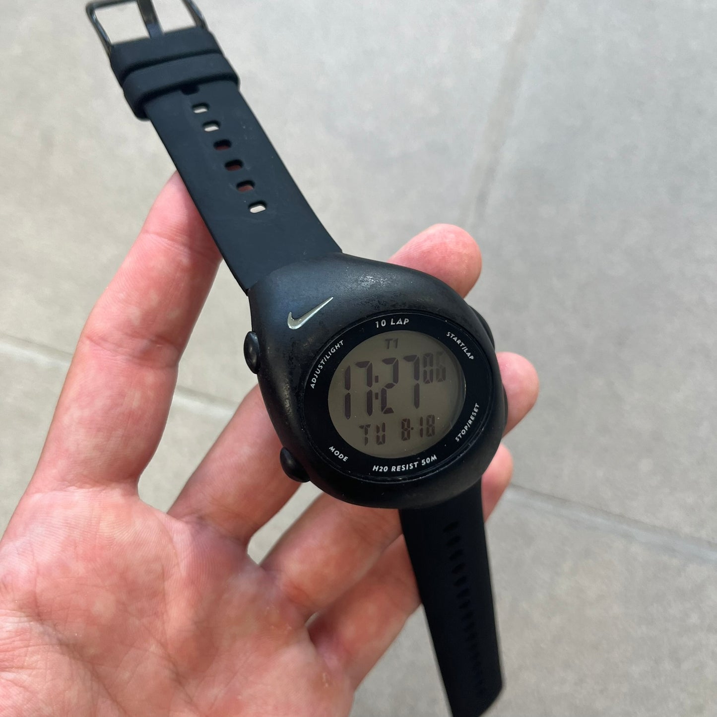 Nike Triax 2000's Super 10 Lap Digital Watch features a black case with a small white Nike Swoosh above the digital display. It has 10-lap memory, four modes, a light-up display, and water resistance. Model WR0005-001. The rubber straps have been replaced with non-original ones.
