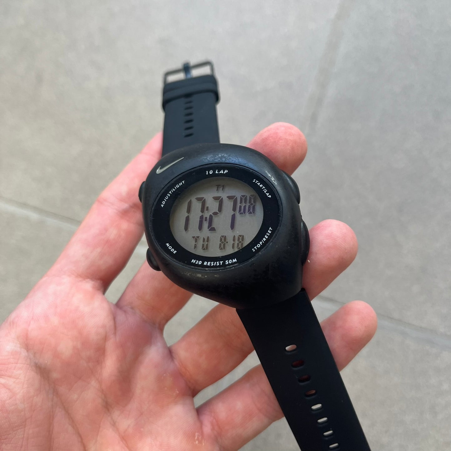 Nike Triax 2000's Super 10 Lap Digital Watch features a black case with a small white Nike Swoosh above the digital display. It has 10-lap memory, four modes, a light-up display, and water resistance. Model WR0005-001. The rubber straps have been replaced with non-original ones.
