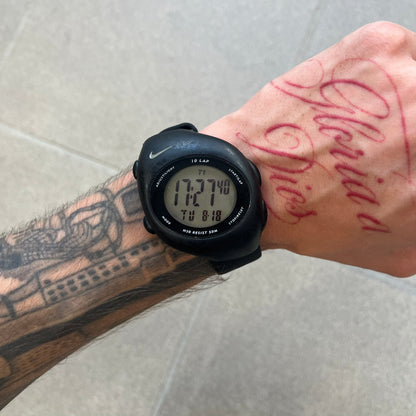 Nike Triax 2000's Super 10 Lap Digital Watch features a black case with a small white Nike Swoosh above the digital display. It has 10-lap memory, four modes, a light-up display, and water resistance. Model WR0005-001. The rubber straps have been replaced with non-original ones.
