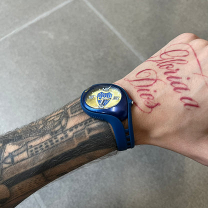 Nike Triax Blaze Boca Juniors WD0055 Analog Watch is a vintage watch featuring a blue rubber strap, metal case, and yellow dial. The dial displays a large full-color Boca Juniors crest with white main numerals, while a yellow Nike Swoosh is positioned at the top of the case. The watch is water resistant up to 50 meters and is constructed from stainless steel and plastic materials.