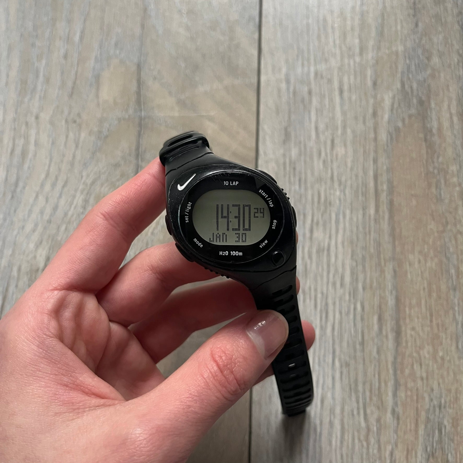 The Nike Triax Bowerman WR0124 Black Digital Watch features black rubber straps and a black plastic case with a metal caseback engraved with the Bowerman logo. It includes a digital display with multiple modes, a 10-lap memory function, H2O 100 water resistance, and a built-in backlight. The watch has a single front button and a white Nike logo on the case.