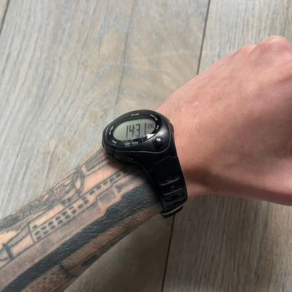 The Nike Triax Bowerman WR0124 Black Digital Watch features black rubber straps and a black plastic case with a metal caseback engraved with the Bowerman logo. It includes a digital display with multiple modes, a 10-lap memory function, H2O 100 water resistance, and a built-in backlight. The watch has a single front button and a white Nike logo on the case.