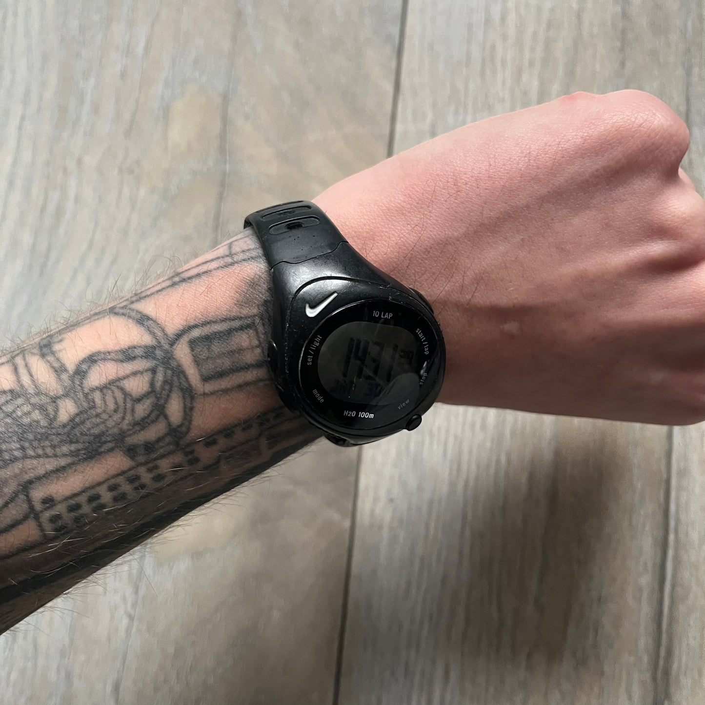 The Nike Triax Bowerman WR0124 Black Digital Watch features black rubber straps and a black plastic case with a metal caseback engraved with the Bowerman logo. It includes a digital display with multiple modes, a 10-lap memory function, H2O 100 water resistance, and a built-in backlight. The watch has a single front button and a white Nike logo on the case.