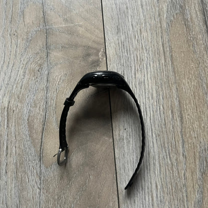 The Nike Triax Bowerman WR0124 Black Digital Watch features black rubber straps and a black plastic case with a metal caseback engraved with the Bowerman logo. It includes a digital display with multiple modes, a 10-lap memory function, H2O 100 water resistance, and a built-in backlight. The watch has a single front button and a white Nike logo on the case.