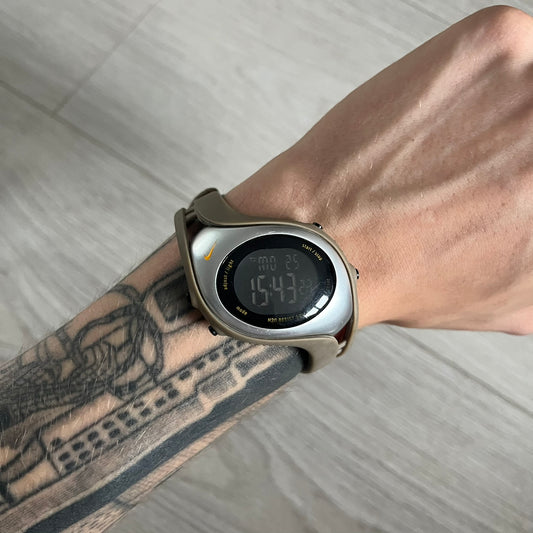 Digital watch on a wrist with tattoos, on a light wooden surface
