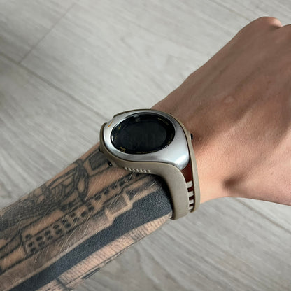 Smartwatch on a wrist with a tattooed arm against a neutral background