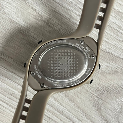 Close-up of a watch case with brand engraving on a light wooden surface