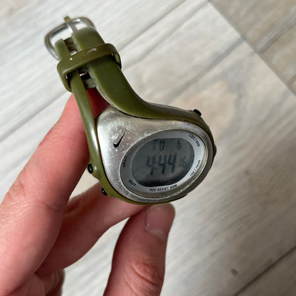 Nike Triax Fly WK0006 Green Digital Watch is a 2000s digital watch featuring a green rubber strap and silver-tone case. It includes multifunction quartz movement, a digital display with backlight functionality, and 50 meter water resistance.
