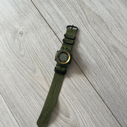 Green watch with a metal face on a light wooden surface
