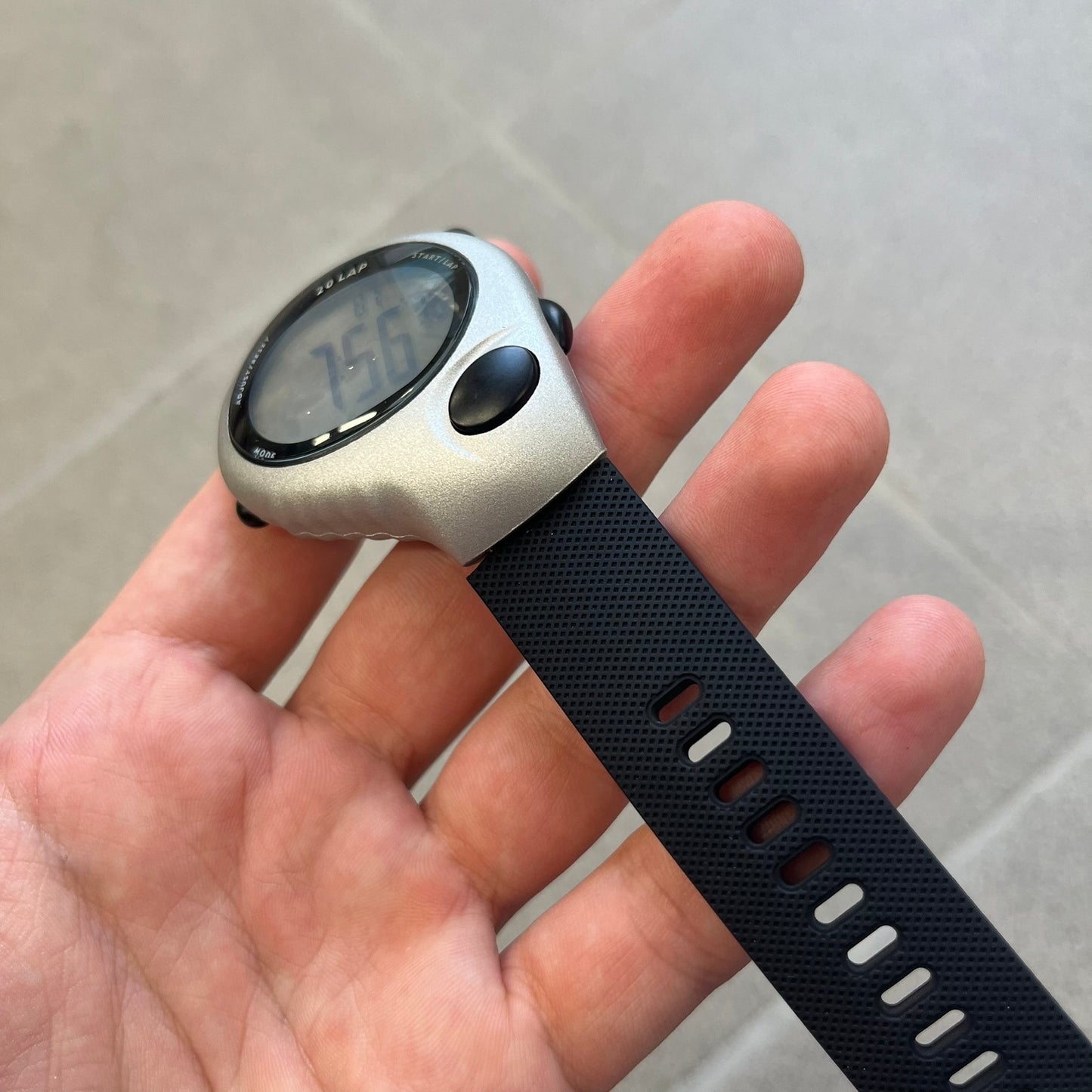 Nike Triax Regular 20 Silver Analog Watch features a silver-tone case with four black side buttons and a front button for the backlight function. The watch has an orange Nike Swoosh on the top of the case, 20-lap memory, multiple modes, and 100m water resistance. It comes with black replacement straps that are not original Nike.

