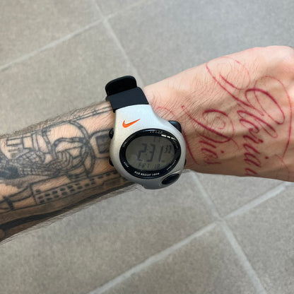 Nike Triax Regular 20 Silver Analog Watch features a silver-tone case with four black side buttons and a front button for the backlight function. The watch has an orange Nike Swoosh on the top of the case, 20-lap memory, multiple modes, and 100m water resistance. It comes with black replacement straps that are not original Nike.
