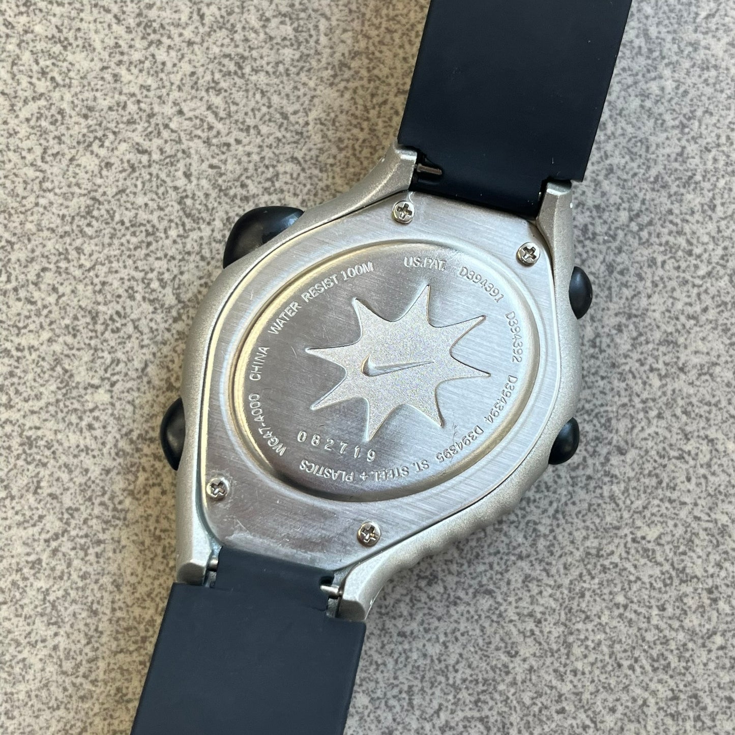 Nike Triax Regular 20 Silver Analog Watch features a silver-tone case with four black side buttons and a front button for the backlight function. The watch has an orange Nike Swoosh on the top of the case, 20-lap memory, multiple modes, and 100m water resistance. It comes with black replacement straps that are not original Nike.

