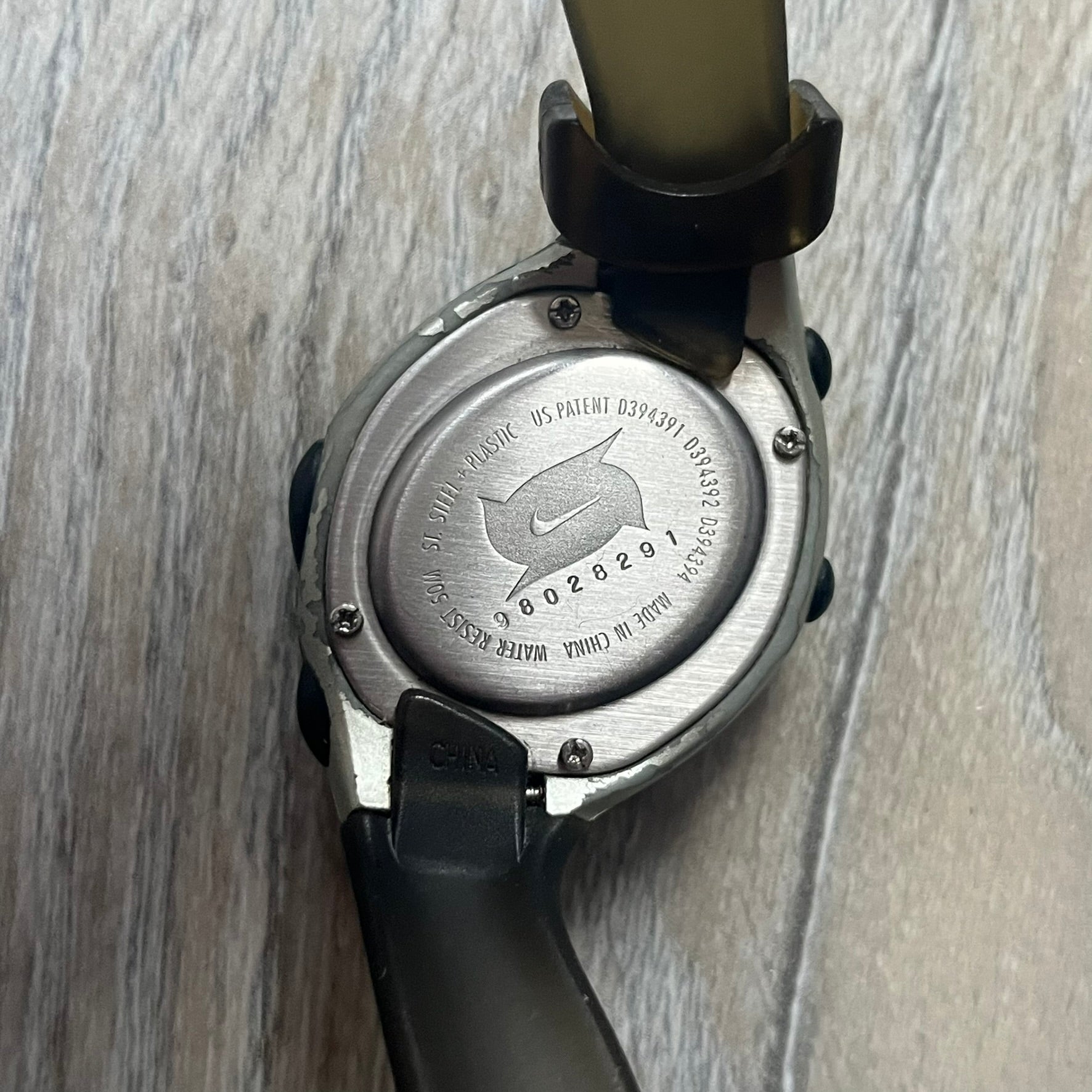 Nike Triax Roar J Digital Watch WR0017 in clear features a sporty design with a dark transparent strap and a silver case. Built for performance, it offers 50m water resistance and an ergonomic fit ideal for active use. The running man logo illuminates in the center of the dial when the lightning button is pressed, adding a distinctive touch.