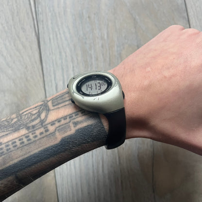 Nike Triax Roar J Digital Watch WR0017 in clear features a sporty design with a dark transparent strap and a silver case. Built for performance, it offers 50m water resistance and an ergonomic fit ideal for active use. The running man logo illuminates in the center of the dial when the lightning button is pressed, adding a distinctive touch.
