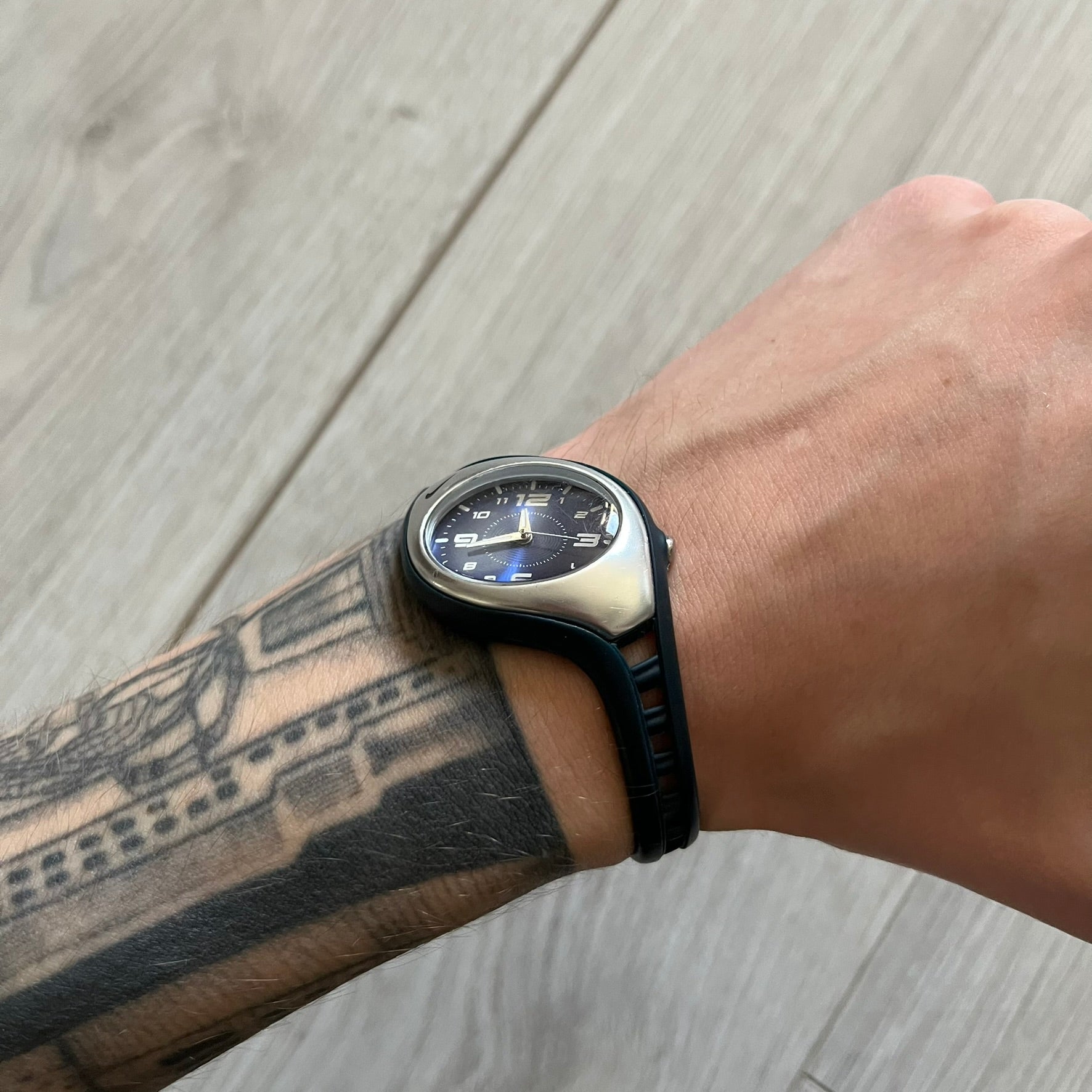 Nike Triax Roar Junior WK0007 analog watch featuring a navy rubber strap with matching navy case sides and a silver-tone front case. The metallic blue dial has a high-shine finish, silver hour markers, and silver hands for clear visibility. Built with stainless steel and metal components, the watch is water resistant up to 50 meters